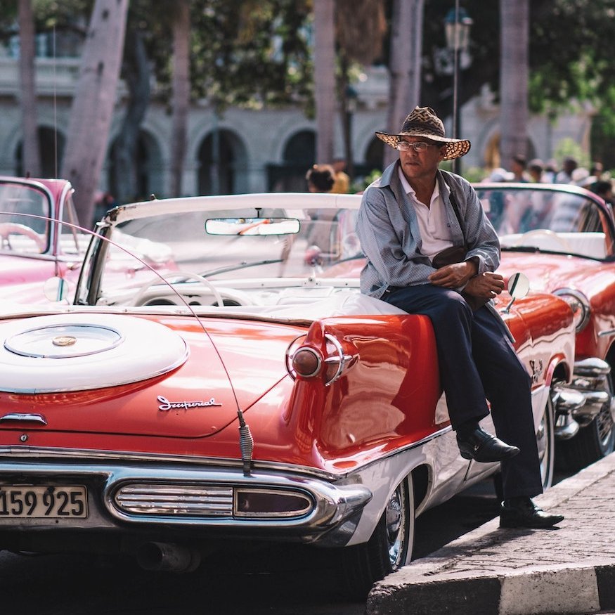 Kuba Oldtimer Mann mit Hut ist an Oldtimer gelehnt