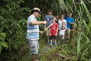Costa Ricaner zeigt einer Familienreisegruppe etwas in der Natur