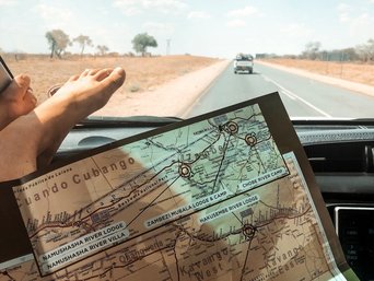 Frau mit Füßen auf dem Armaturenbrett schaut auf einer Karte beim Autofahren