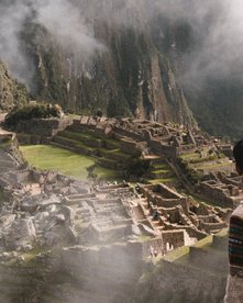 Mann schaut auf die Inka Stadt Machu Picchu, die mit wolken verhangen ist
