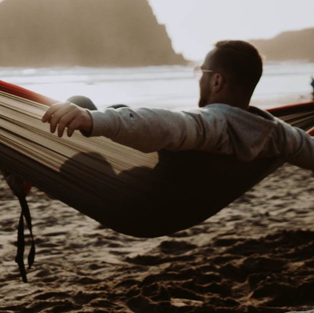 Nicht erkennbarer Mann liegt in einer Hängematte am Meer