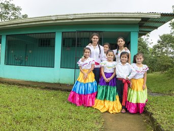 Schulkinder in bunten Kleidern vor der Escuela San Jorge bei La Tigra