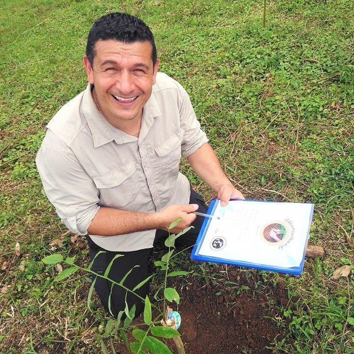 Adolfo pflanzt in La Tigra einen Baum und zeigt das Zertifikat dazu.