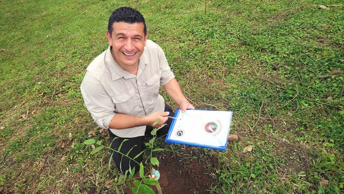 Adolfo pflanzt in La Tigra einen Baum und zeigt das Zertifikat dazu.