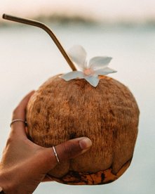 Tansania Sansibar Kokosnuss Frau hält Kokosnuss mit Röhrchen in der Hand