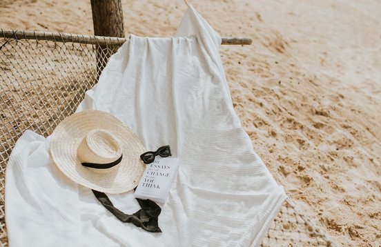 Sonnenbrille, Gut und Buch liegen auf einer Decke in einer Hängematte
