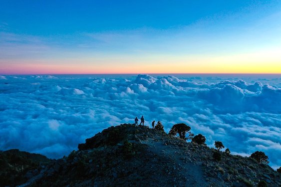 Menschen auf einem Berg über den Wolken bei Sonnenaufgang