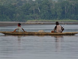 Zwei Einheimische fahren mit Holzkanu über Fluss
