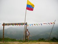 Trekking zur Ciudad Perdida, Frau steht an der kolumbianischen Flagge