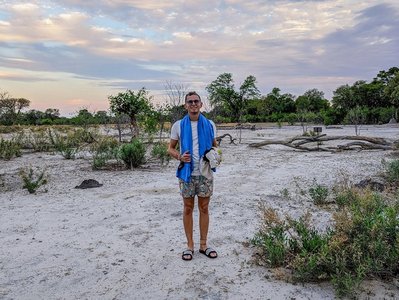 Mann steht mit Adiletten in Savanne