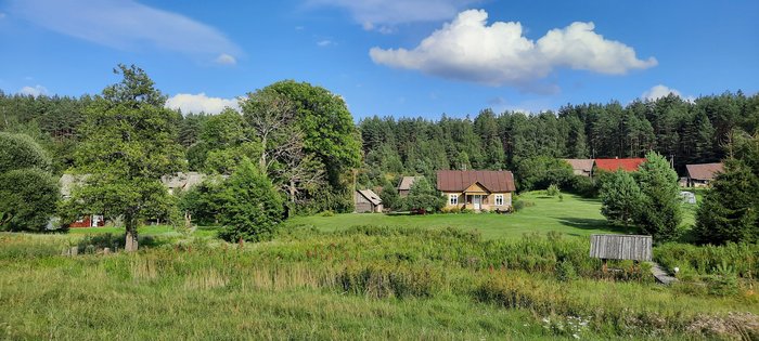 Malerisches Dorf zwischen sanften grünen Hügeln und blauem Himmel in Litauen