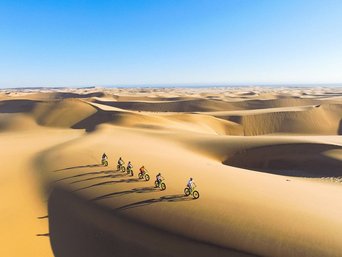 Drohnen Bild zeigt Menschen auf Fatbike von oben in Wüste