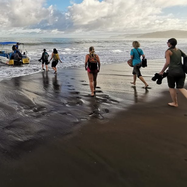 Reisegruppe läuft zu einem Boot am Strand von Corcovado in Costa Rica