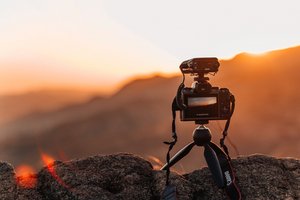 Kamera auf kleinem Stativ fotografiert einen Sonnenuntergang