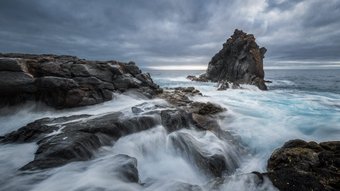 Langzeitbelichtung eines großen Felsens im Meer
