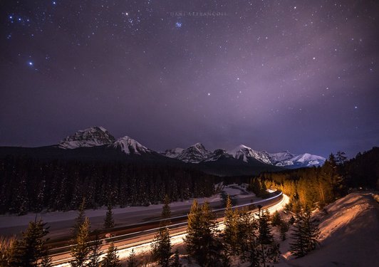 Sternenhimmel über der verschneiten landschaft und einer beleuchteten Straße
