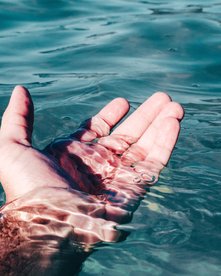 Mensch im Meer streckt die Hand im Wasser aus