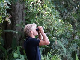 Blonder Mann schaut durch ein Fernglas und beobachtet Vögel