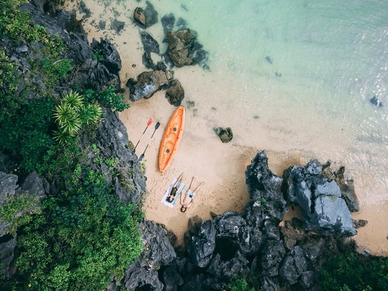 Zwei Personen mit Kayak liegen am Strand