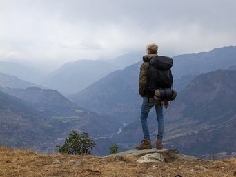 Junger Mann von hinten wie er in ein Tal schaut