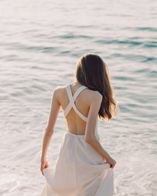 Frau in weißem Kleid läuft am Strand
