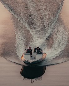 Schnellboot fährt auf glattem Meerwasser bei Sonnenuntergang